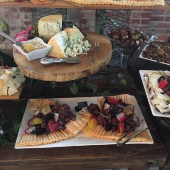 Display of cheeses and fruits on a table.