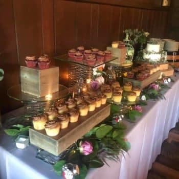 Cupcakes on a table for an event. There are various flowers.