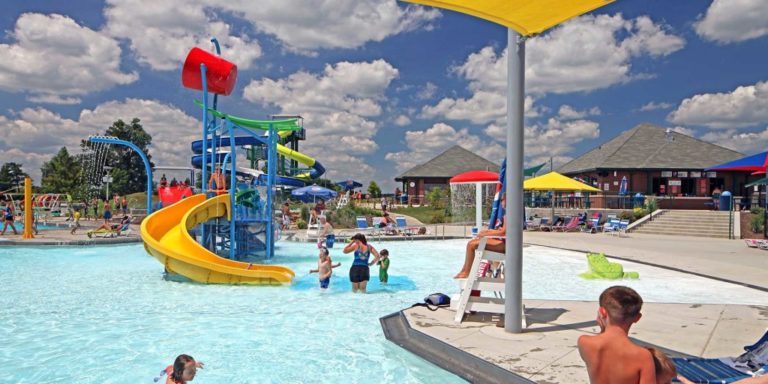 kids playing in an the water of the Aquatic center. water slides to the left.