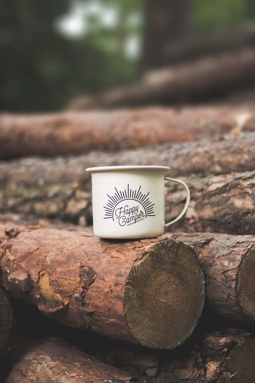 logs for firewood with coffee cup on them that reads Happy Camper