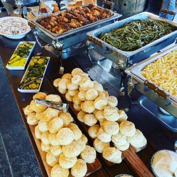 A catering set up at an event. There are biscuits, green beans, mac and cheese, chicken, and more.