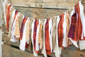 pieces of materials tied on a line, all with different colors and patterns. Distressed wood as a backdrop