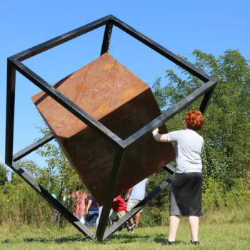 Kids interacting with metal, cube sculpture.