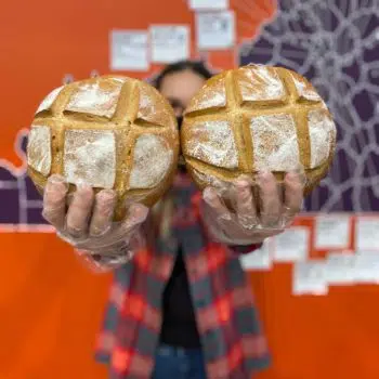 person holding two fresh loaves of bread from Locals Food Hub and Pizza Pub