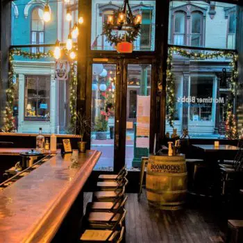Inside of restaurant with view of the copper- topped bar on the left, booths on the right, and the downtown street straight ahead