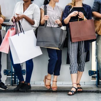 shopping bags of different shapes, colors and sizes held by people of different genders and ethnicity