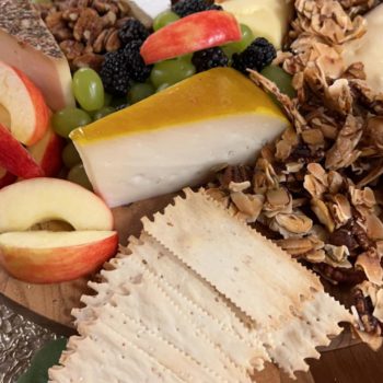Cheese, apples, nuts, and fruit on a charcuterie board.