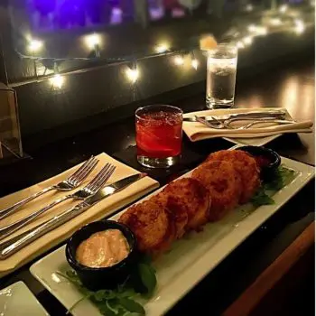 plate of fried green tomatoes, accompanied by remoulade sauce. Twinkling outdoor lights in background