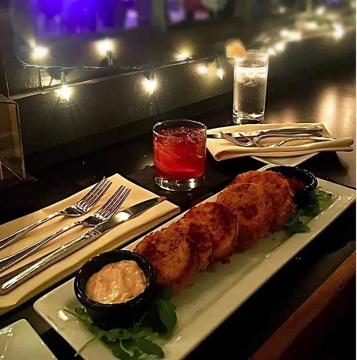 plate of fried green tomatoes, accompanied by remoulade sauce. Twinkling outdoor lights in background